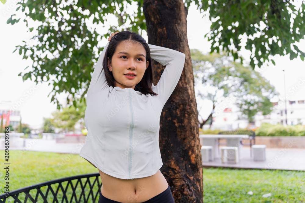 Fototapeta premium Asian sporty woman stretching before workout in public park