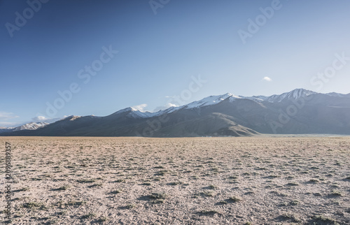 Fotografie A desert landscape in the highlands of the Pamirs on a sunny summer day with mou