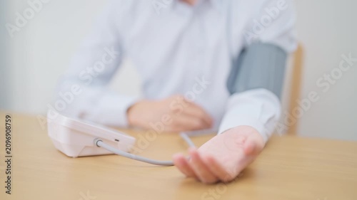 Man checking Blood pressure by Blood pressure monitor with Cuff. Systolic, SYS, Diastolic, DIA, Pulse, Hypertension, Hypotension, Heart rate, Cardiovascular Disease and May World hypertension day