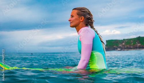 Young Woman Surfer Waiting for Waves in Colorful Wetsuit Side View