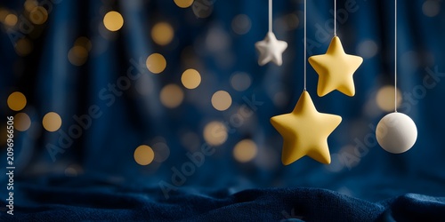 Hanging yellow stars and white decorations on strings against blue background with bokeh lights