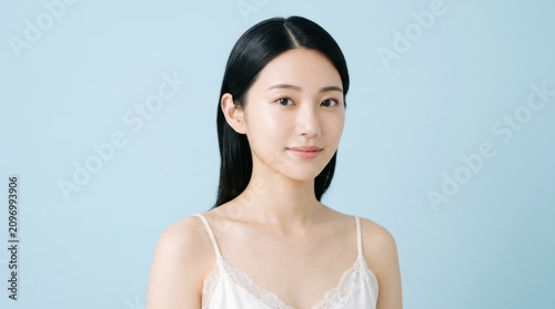 Portrait of a young asian woman with clear skin against a blue background
