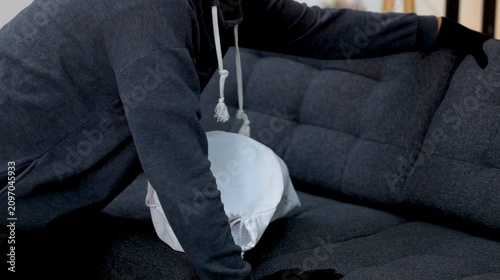 Fotografi Masked Intruder in Dark Hoodie Searching a Sofa with White Bag