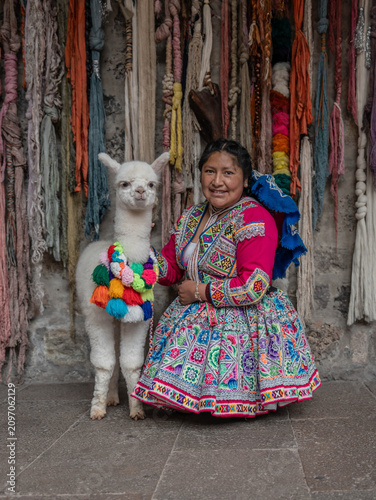 Woman posing with an alpaca in the historic city of Cusco, Peru, surrounded by traditional Andean architecture, showcasing local culture, tourism and the cultural heritage of the Peruvian Andes.