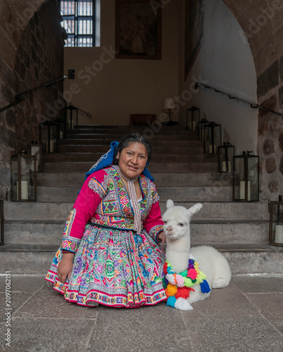Woman posing with an alpaca in the historic city of Cusco, Peru, surrounded by traditional Andean architecture, showcasing local culture, tourism and the cultural heritage of the Peruvian Andes.