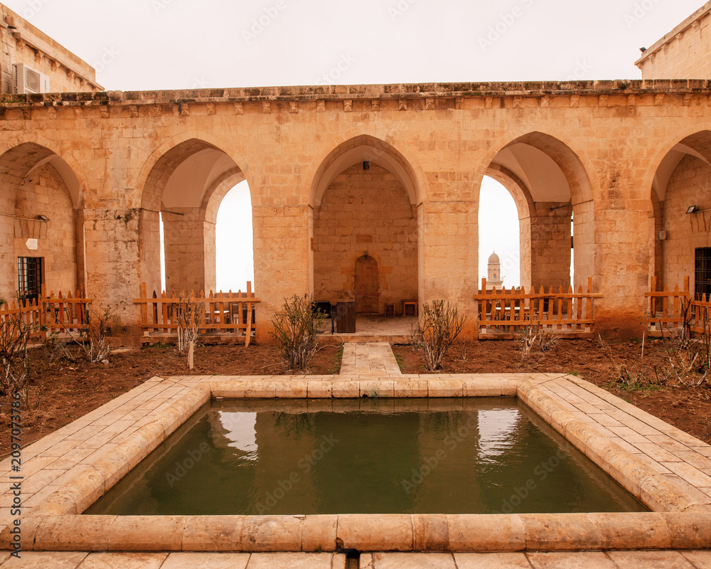 Fototapeta premium Historic Stone Courtyard with Ancient Arches and Traditional Middle Eastern Architecture , Historic Courtyard Architecture
