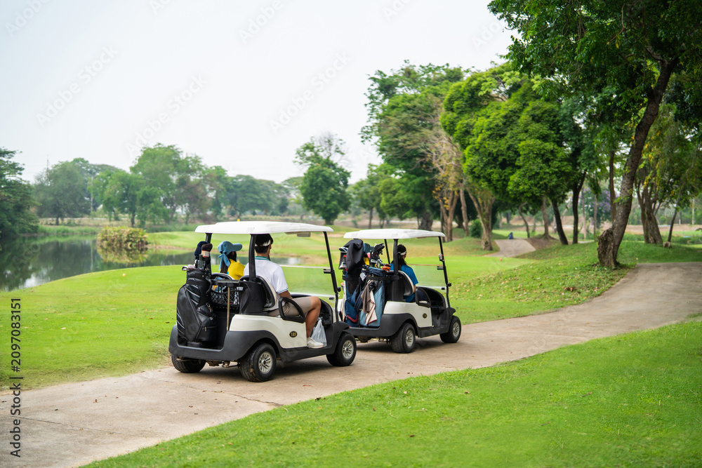 Obraz premium Group of golfers ride together in golf cart on scenic golf course.