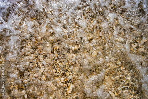 Foamy seawater washing over a pebble beach on the Adriatic coast of the Marche region, Italy, creating a natural background with dynamic texture and motion