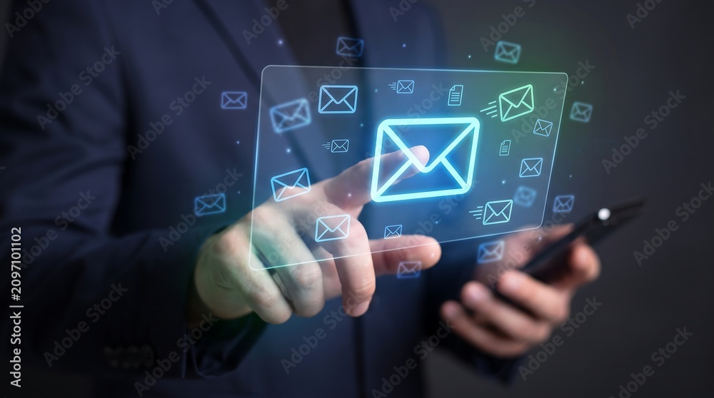 Fototapeta premium Businessman touching a holographic email interface display while holding his smartphone in a dark professional setting representing digital communication and modern workflow systems