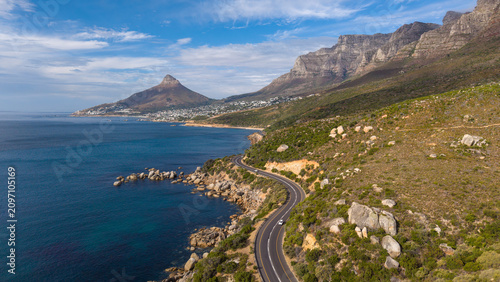Scenic winding coastal road south of Camps Bay, South Africa, beneath a clear blue sky. Lion's Head and Camps Bay form a spectacular backdrop to one of Cape Town's most iconic coastal drives.