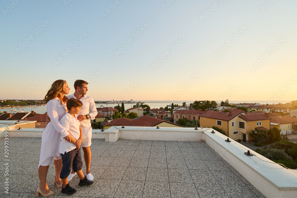 Obraz premium Family on Rooftop Balcony Overlooking Umag Seaview at Sunset Together on Terrace