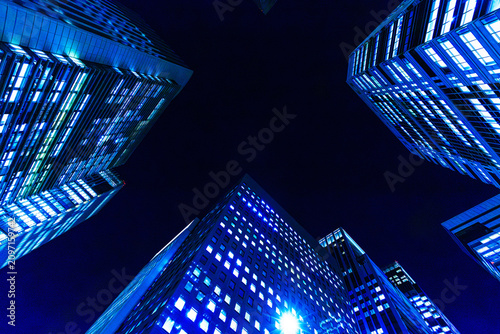 Futuristic cyber-blue city skyline of Tokyo's financial district from a dynamic looking-up perspective.