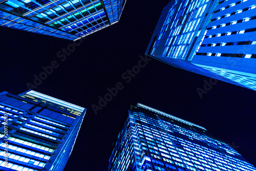 Futuristic cyber-blue city skyline of Tokyo's financial district from a dynamic looking-up perspective.