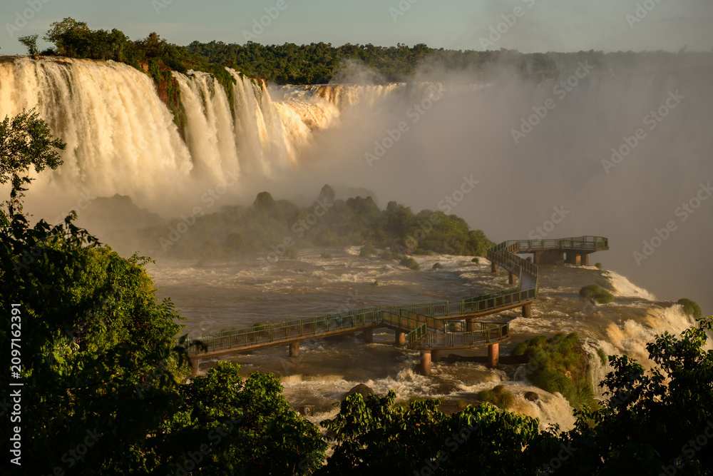 Obraz premium Breathtaking iguazu falls create majestic nature landscape with mist covering wooden walkway