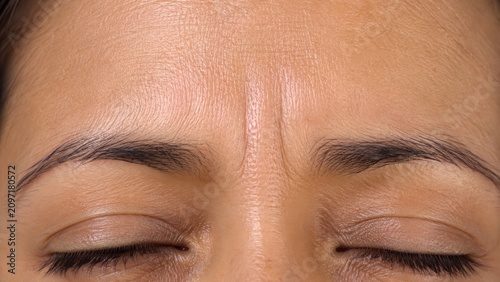 Close-up of wrinkled forehead with closed eyes showing skin texture and expression lines