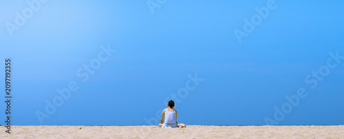 Foto Blue sunny sky, warm orangey beach with a girl sunbathing