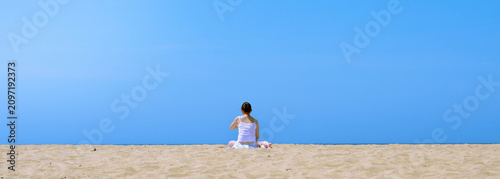 Schilderij op canvas Blue sunny sky, warm orangey beach with a girl sunbathing