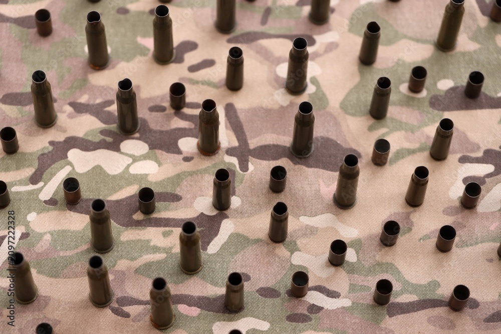 Fototapeta premium Big amount of shells cartridges from assault rifle bullets on old camouflage fabric