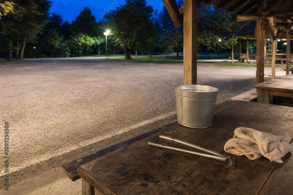Naklejka premium 夜の公園管理に備えた水バケツと長い火ばさみ
