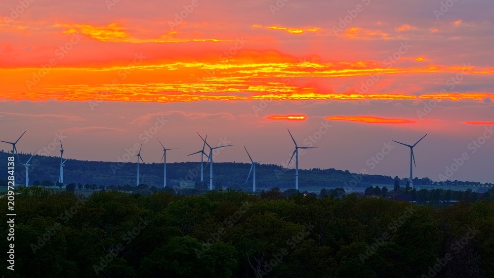 Obraz premium Wind Turbines at Dramatic Golden Sunset Over Green Fields