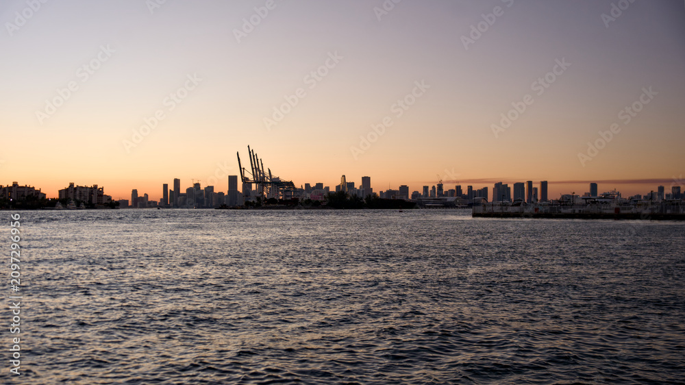 Fototapeta premium The Miami downtown skyline glows at sunset with calm water in the foreground