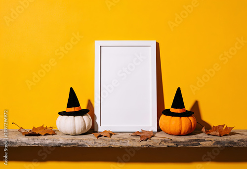 Halloween themed pumpkins with witch hats and empty frame on wooden shelf