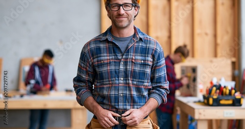 Confident carpenter in workshop with team