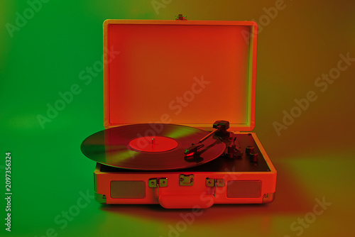Foto Vintage record player with vinyl disc spinning under colorful lighting