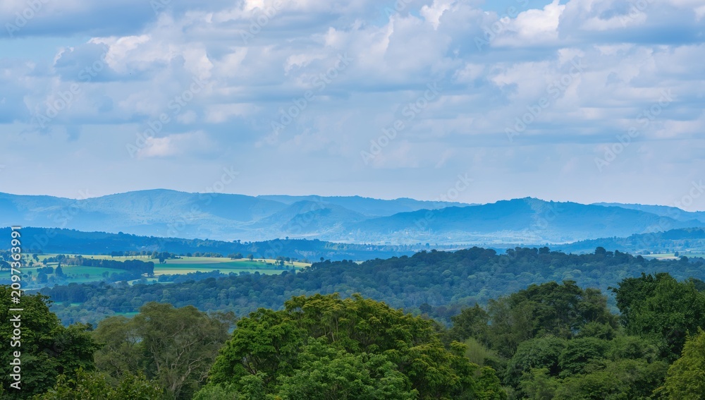 Obraz premium Mountainous Landscape Under Bright Blue Sky with Fluffy White Clouds