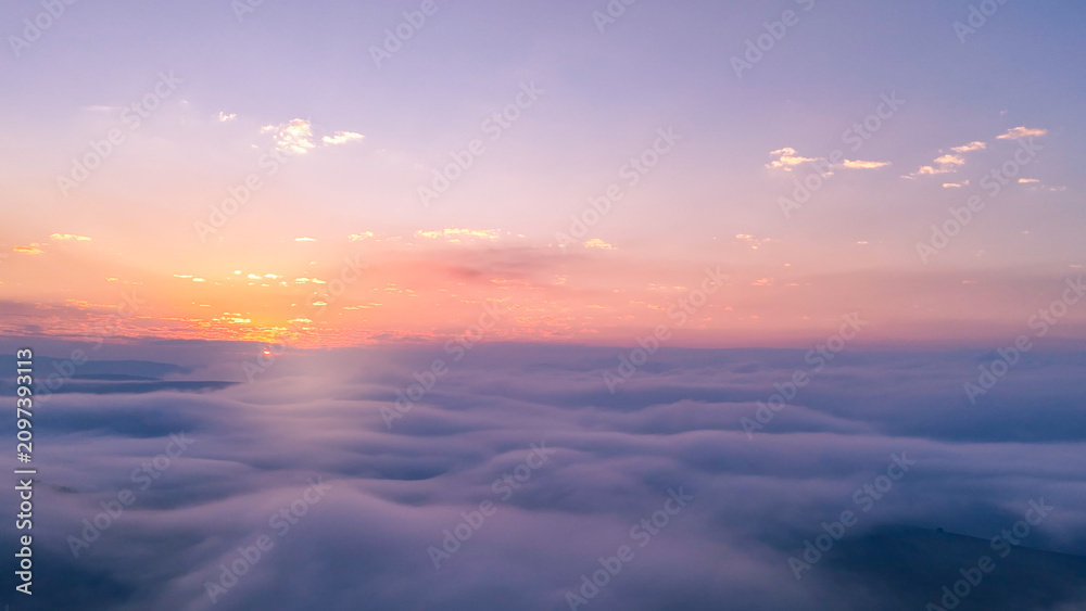 Fototapeta premium Turquoise and pink morning haze enveloping mountains and valleys below