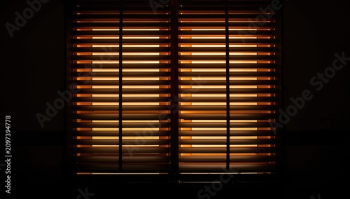 Illuminated Wooden Blinds Casting Shadows in a Dark Room