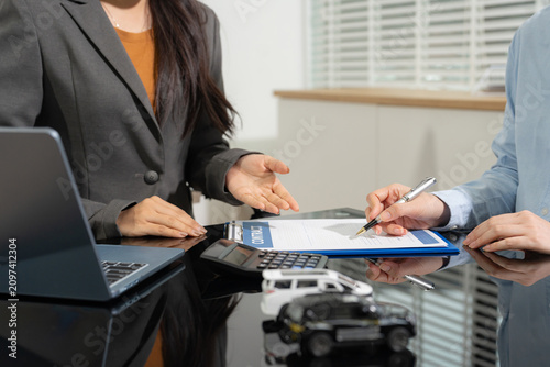 Happy young Asian woman signing car loan agreement with financial agent.