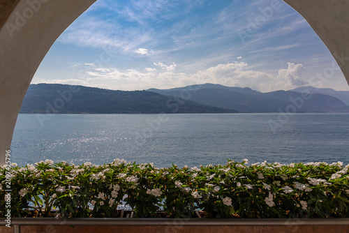 Konstfotografi Scenic View of Lake Maggiore through Elegant Arched Loggia with Flowers