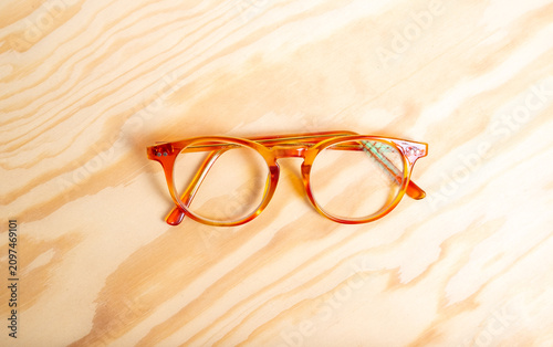 Fotografía Amber round eyeglasses resting on light wood table