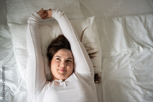 Young woman relaxing while stretching in bed as part of her morning routine. Sleep wellness and a healthy lifestyle focused on positive awakening and comfort