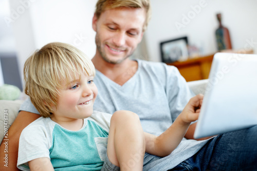 Tablet, cartoon and father with child on sofa in home for streaming service, pointing and relax. Movie subscription platform, online media app and weekend break with dad and happy kid in living room