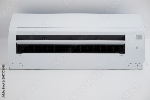 Straight-on shot of a modern white ductless split air conditioner unit with its air flap open.