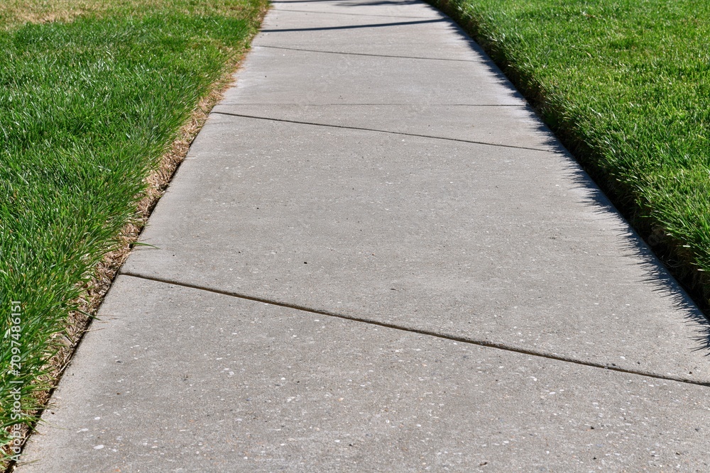 Obraz premium The Concrete Sidewalk Leading Through Green Lawns On A Sunny Day