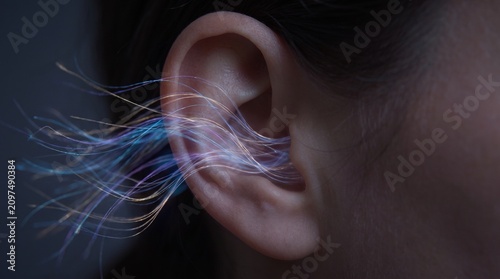 A close-up view of a person's ear with vibrant blue and purple streaks emanating from it in a dark environment.