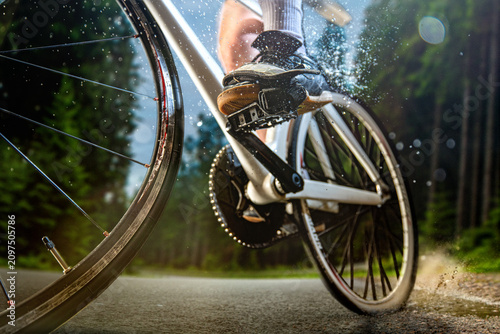 фотографія Close-up road bicycle crankset and rear wheel splashing through puddle on forest road