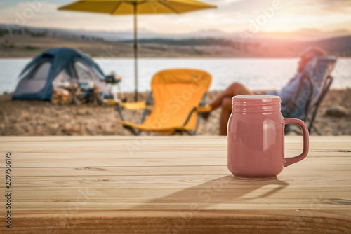 Lake camping with mountain view and wooden table with copy space – outdoor summer adventure concept.