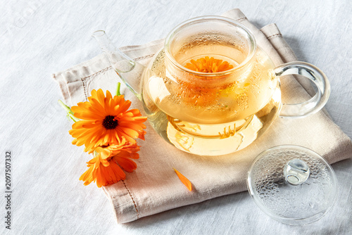 Calendula tea. Vibrant orange marigold flowers infusing in a clear glass teapot