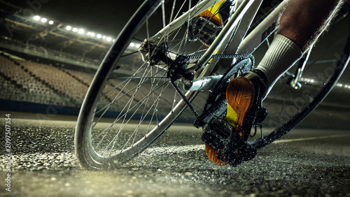 Fotografía Close-up bicycle drivetrain and rear wheel on wet velodrome track under stadium lights