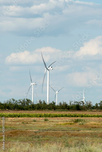 Modern wind power turbine generator against blue sky, alternative sustainable energy concept.
