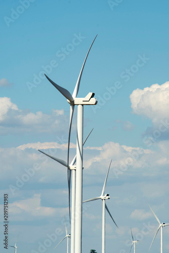 Modern wind power turbine generator against blue sky, alternative sustainable energy concept.
