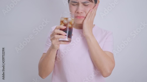 Woman drinking carbonated ice water and feeling sensitive teeth to cold pain, hand holding glass of cold sparkling water. dental health problem from soda acidity, toothache and oral care concept