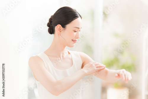 ボディーケア。腕にクリームを塗る女性