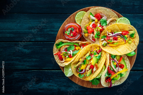 Mexican tacos with pulled chicken, avocado, chili peppers, and red salsa, overhead flat lay shot, with a place for text