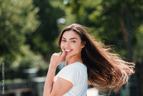 Obraz na plátně Smiling young woman outdoors with long flowing hair enjoying a sunny summer day
