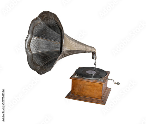 An old vintage gramophone with a large metal horn and a vinyl record sits on a wooden base isolated on a white background.